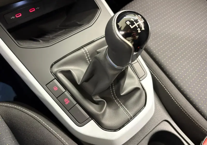 Gros plan sur le levier de vitesses manuel et la console centrale du SEAT Arona 2023 avec sellerie noire à surpiqûres blanches.