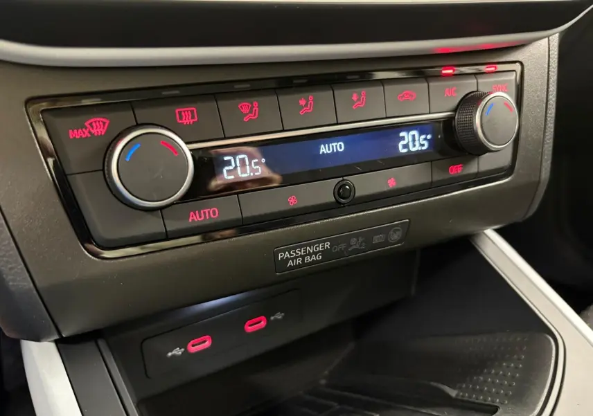 Détail du tableau de bord de la SEAT Arona 2023 montrant la climatisation automatique avec affichage digital et commandes rouges.
