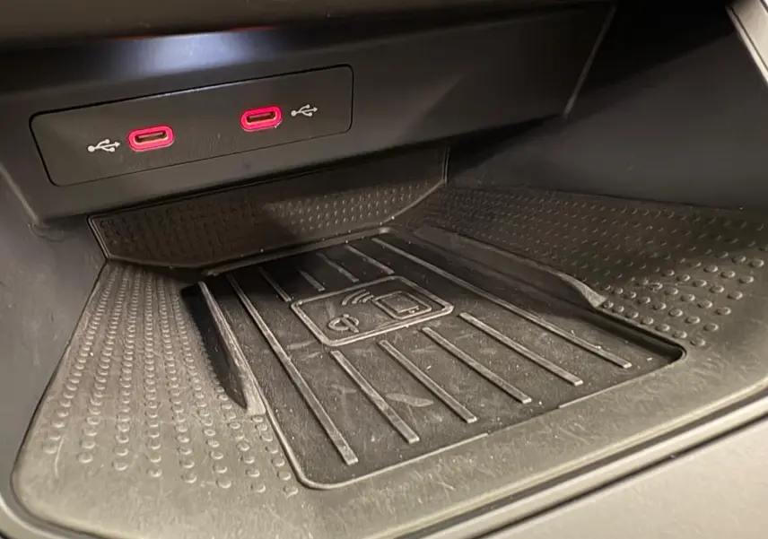Gros plan sur la zone de recharge sans fil et les deux ports USB rouges dans l'habitacle du SEAT Arona 2023.