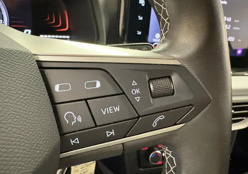 Gros plan sur les commandes au volant en cuir noir avec surpiqûres blanches du SEAT Arona blanc toit noir 2023.