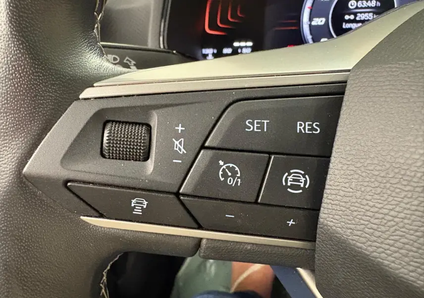 Gros plan sur les commandes de régulateur de vitesse au volant du SEAT ARONA 2023 blanc toit noir.