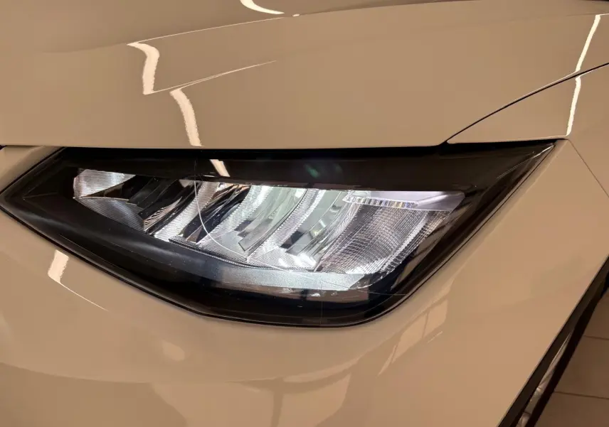 Gros plan sur le phare avant droit du SEAT Arona blanc avec toit noir, soulignant le design moderne et épuré.