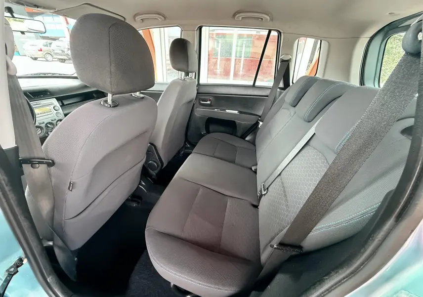 Vue intérieure arrière montrant les sièges en tissu noir de la Mazda2 gris 5 portes, avec ceintures de sécurité visibles.