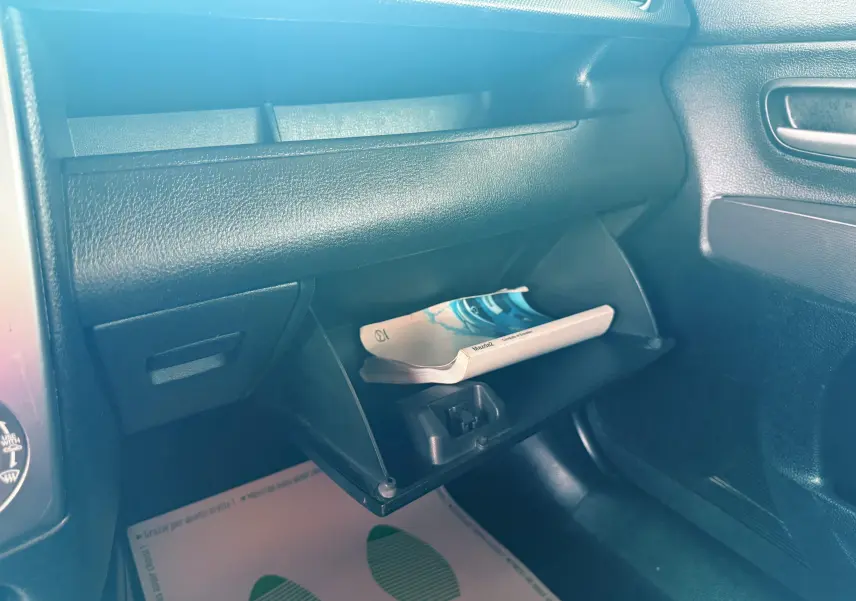 Gant de boîte à gants ouvert côté passager avec manuel d'utilisation dans l'habitacle noir d'une Mazda2 gris 2004.