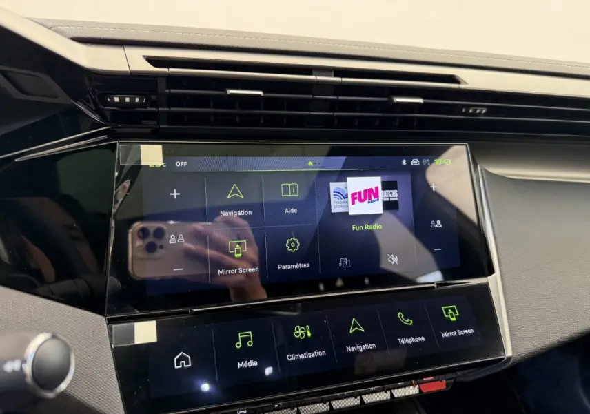 Vue rapprochée de l'écran tactile central 10 pouces du tableau de bord noir de la Peugeot 308 Hybrid 136 e-DCS6 GT blanche 2024.