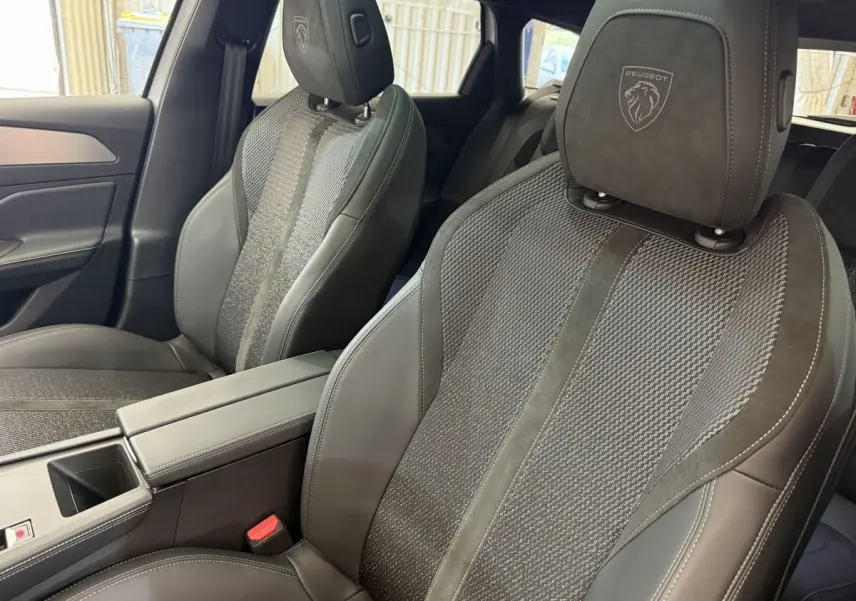 Gros plan sur les sièges avant noirs en cuir et tissu de la Peugeot 308 Hybrid 136 e-DCS6 GT 2024.