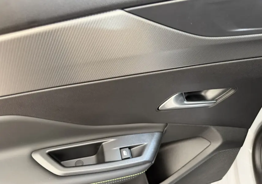 Détail de la porte côté conducteur de la Peugeot 308 Hybrid 136 e-DCS6 GT blanche avec bouton de verrouillage et poignée argentée.