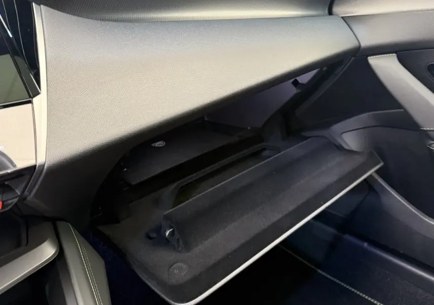 Intérieur Peugeot 308 Hybrid 136 e-DCS6 GT 2024, vue sur boîte à gants ouverte côté passager, finition noire élégante.