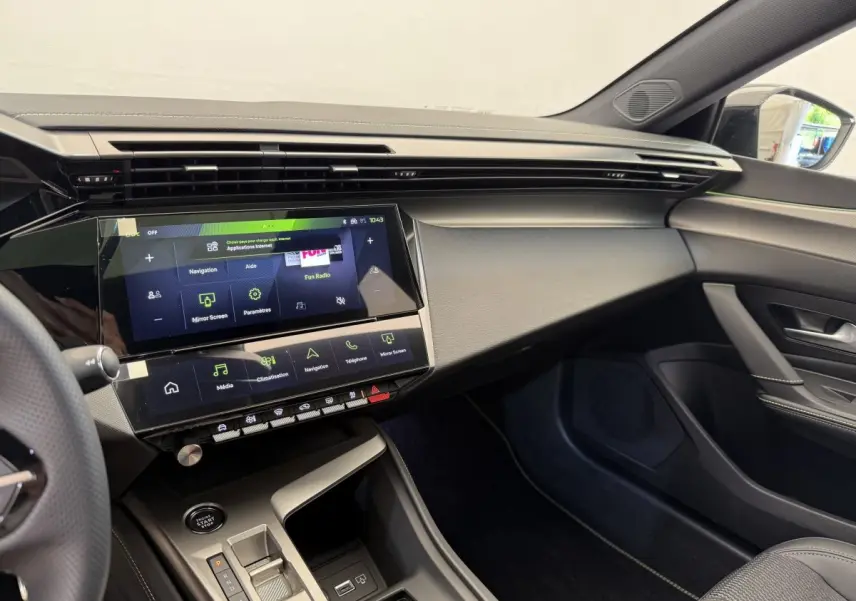 Vue intérieure côté passager du tableau de bord noir et écran tactile 10 pouces de la Peugeot 308 Hybrid 2024 blanche