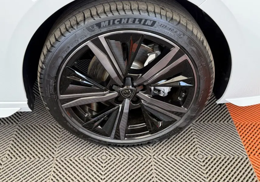 Gros plan sur la roue avant droite de la Peugeot 308 Hybrid 136 e-DCS6 GT blanche avec jante noire brillante au design moderne.