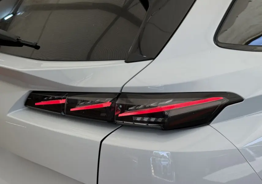 Gros plan sur le feu arrière droit rouge et noir d'une Peugeot 308 Hybrid 136 e-DCS6 GT blanche de 2024.