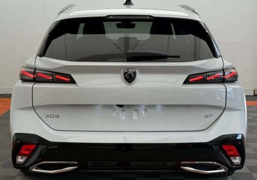 Vue arrière d'une Peugeot 308 GT blanche avec feux LED distinctifs et double sortie d'échappement chromée.