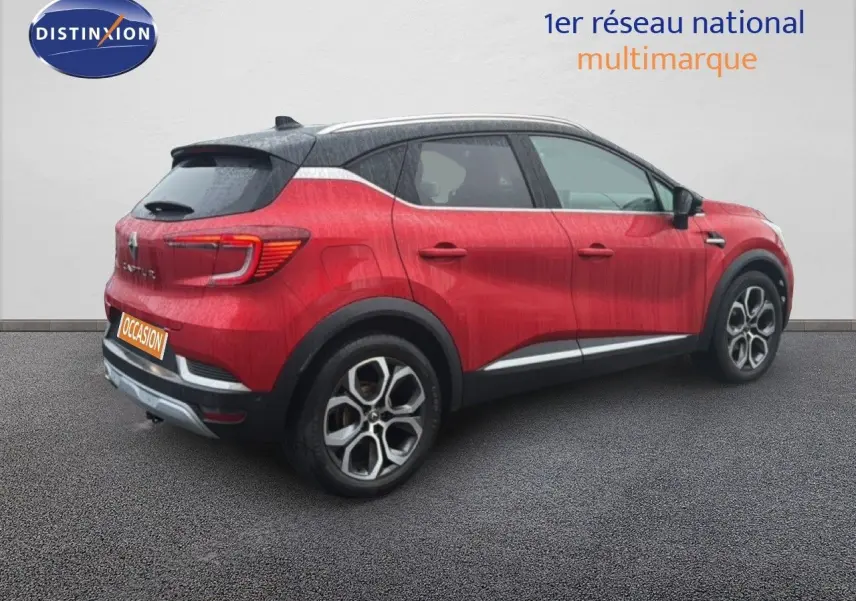 Vue 3/4 arrière droite d’un Renault Captur rouge flamme avec toit noir et jantes bi-ton distinctives.