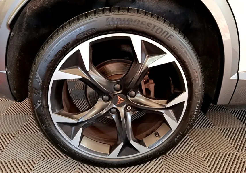 Gros plan sur la jante alliage noire et argentée avec logo CUPRA, montée sur pneu Bridgestone, partie avant droite visible.