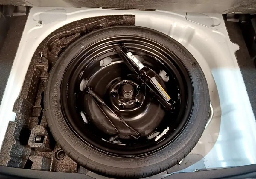 Gros plan sur la roue de secours galette noire dans le coffre blanc d'une CUPRA Formentor 2023.