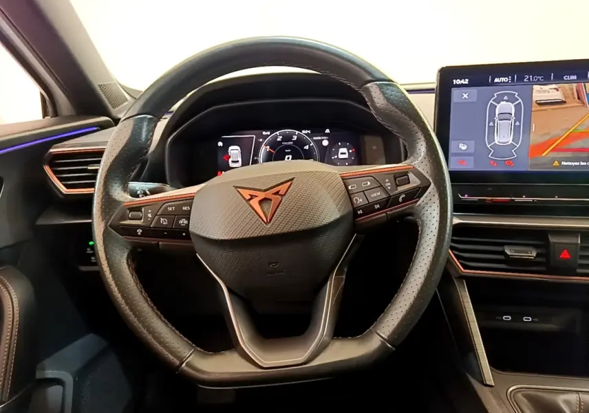 Vue intérieure centrée sur le volant cuir perforé noir avec logo CUPRA et tableau de bord numérique lumineux.