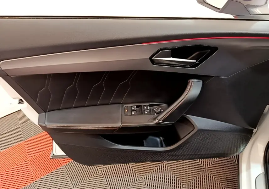 Vue intérieure côté gauche de la porte avant d’une CUPRA Formentor 2023 avec garniture noire et éclairage d’ambiance rouge.