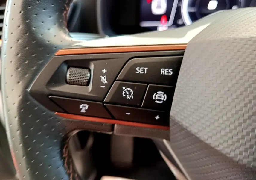 Gros plan sur les commandes du volant cuir noir perforé du CUPRA Formentor 2.0 TDI 2023 avec boutons multifonctions.