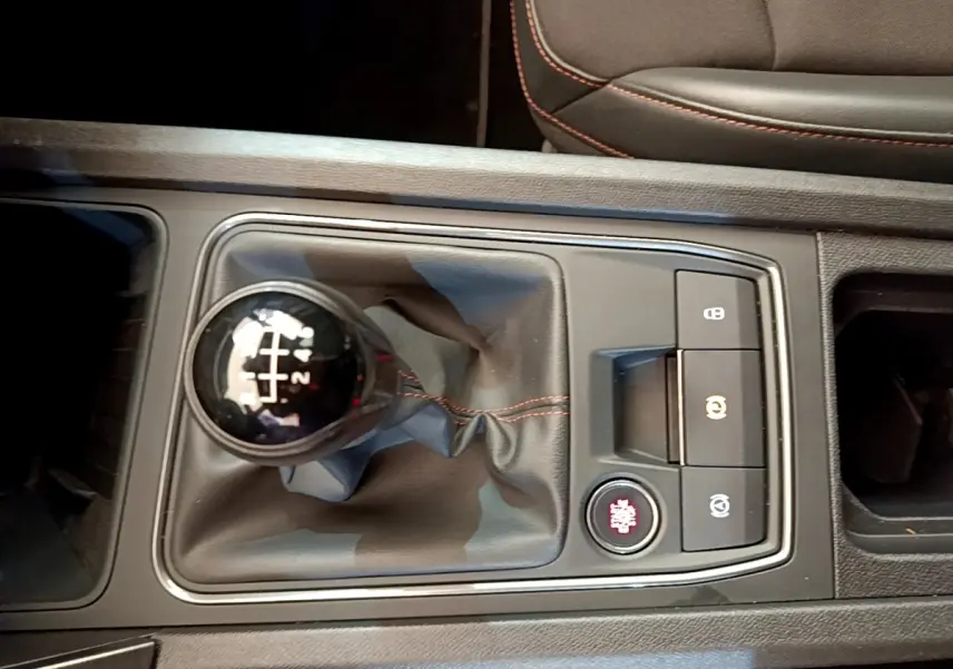 Vue rapprochée de la commande de boîte manuelle noire avec surpiqûres rouges dans une CUPRA Formentor 2023.