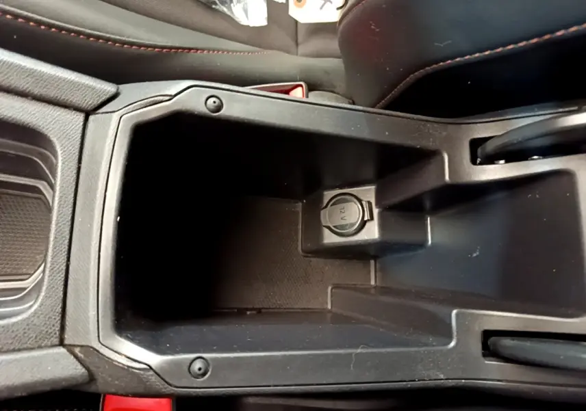 Vue rapprochée de la console centrale noire du CUPRA Formentor 2023 avec prise 12V visible et surpiqûres rouges sur les sièges.