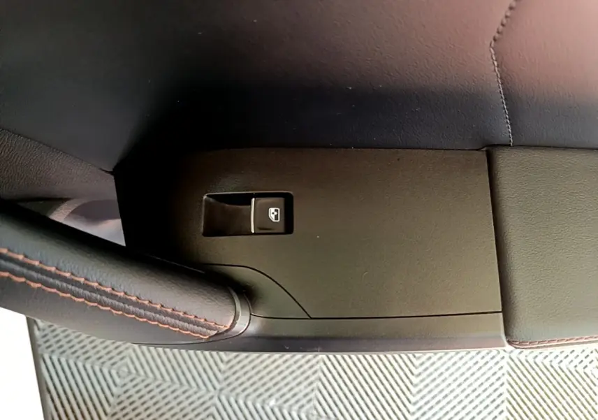 Détail de la commande de lève-vitre côté conducteur sur panneau noir avec surpiqûres rouges dans l’habitacle d’un CUPRA Formentor.