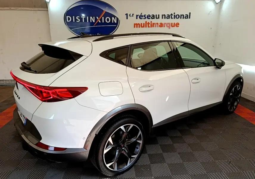 Vue 3/4 arrière droite d'un CUPRA Formentor blanc avec toit noir et jantes alliage noires en showroom.