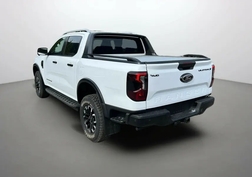 Ford Ranger 2025 blanc glacier en 3/4 arrière droit avec ridelle coulissante et jantes noires.