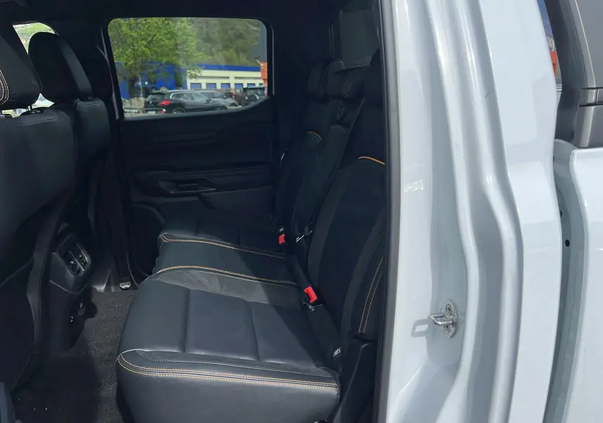 Vue intérieure côté droit sur la banquette arrière en cuir noir avec surpiqûres orange du Ford Ranger blanc glacier 2025.