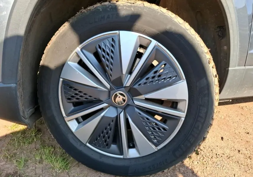 Vue 3/4 arrière droite d'un Skoda Karoq gris 2023 avec jantes alu 17 pouces et feux arrière LED dans un showroom.