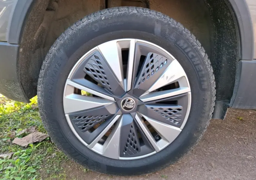 Vue 3/4 arrière droite d'un Skoda Karoq gris 2023 avec jantes alu 17'' et feux arrière LED dans un garage.