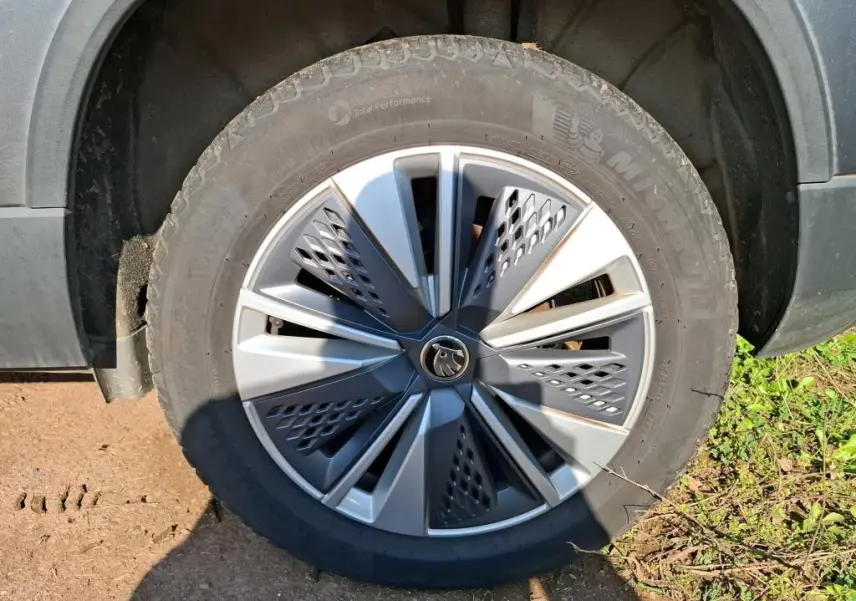 Vue de profil côté gauche d'un Skoda Karoq gris 2023 avec jantes alu 17 pouces dans un garage.