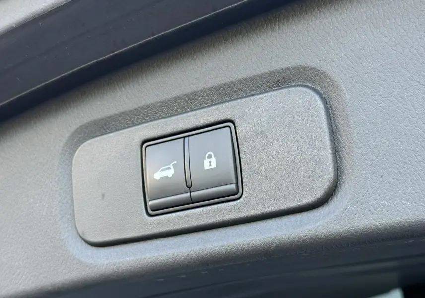 Gros plan sur les boutons d'ouverture électrique du hayon et de verrouillage dans l'habitacle du Nissan Qashqai blanc nacré.