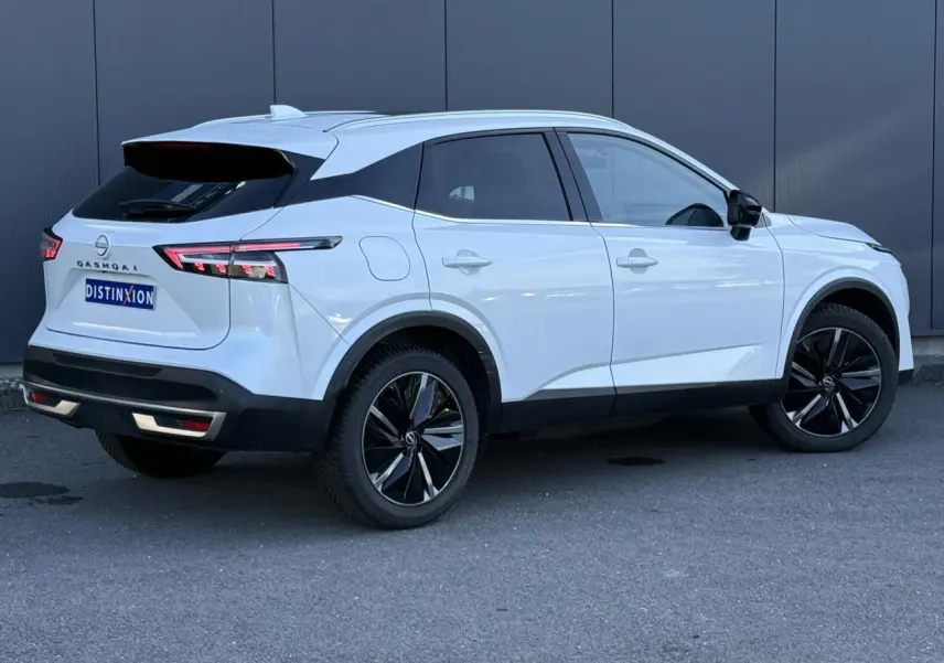 Nissan Qashqai blanc nacré en 3/4 arrière droit, avec jantes alliage noires et feux arrière LED distinctifs.