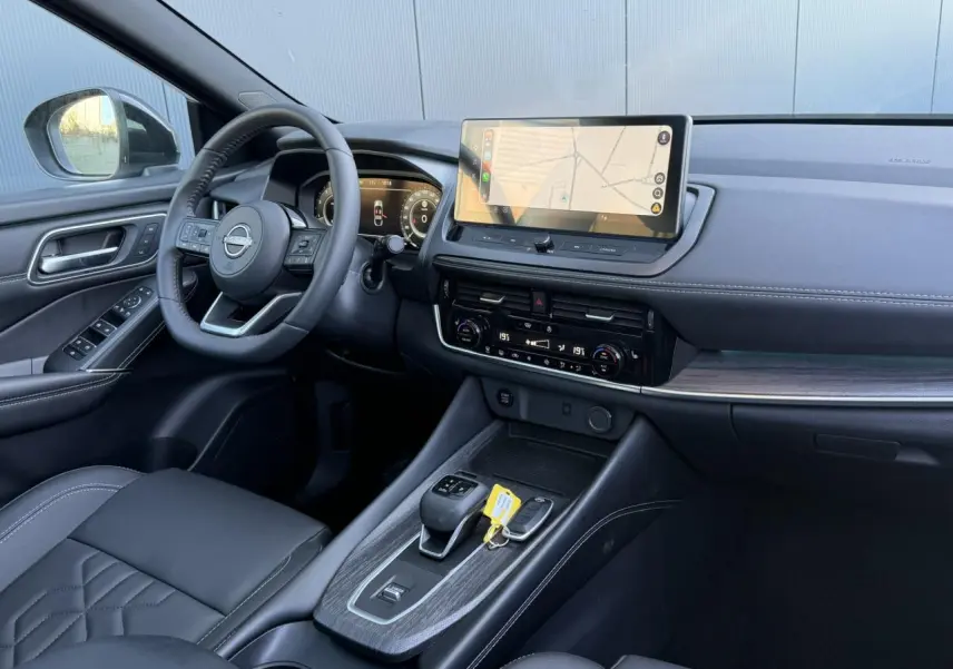 Intérieur noir du Nissan Qashqai 2025 vu côté conducteur, avec écran tactile GPS et volant cuir multifonctions.