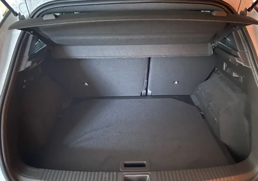 Coffre ouvert vu de l'arrière d'un Renault Austral E-Tech 200 Techno blanc nacré, intérieur noir et tapis de sol.
