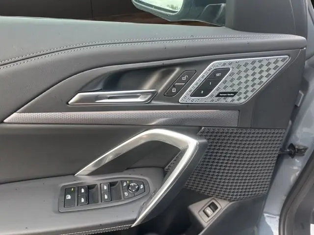 Détail de la porte côté conducteur du BMW X1 Storm Bay 2024, avec commandes mémoire sièges et haut-parleur Harman Kardon.
