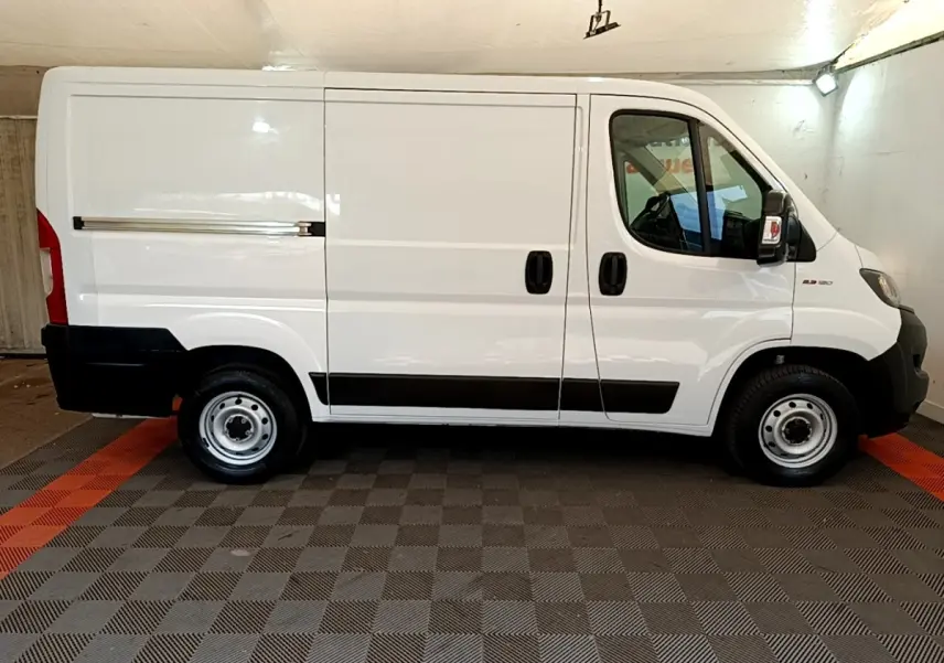Profil droit du FIAT Ducato Fourgon blanc 2021 avec bandeaux noirs et jantes acier simples.
