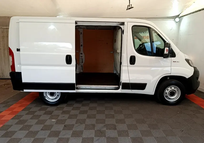 Vue latérale gauche d’un FIAT Ducato Fourgon blanc 2021 avec porte coulissante ouverte montrant l’espace de chargement.