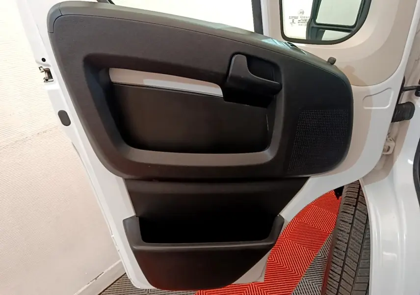 Vue rapprochée de la porte avant droite blanche du Fiat Ducato Fourgon 2021, avec panneau intérieur noir et poignée intégrée.