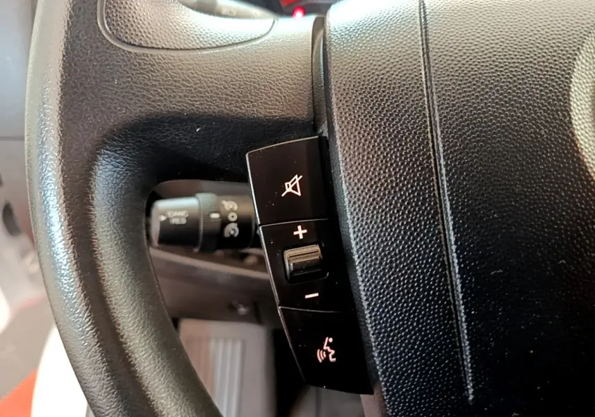 Gros plan sur le volant noir multifonctions du Fiat Ducato Fourgon blanc, montrant les commandes de volume et de son.