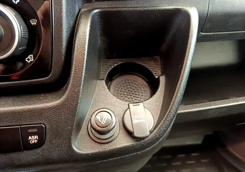 Détail de la console centrale noire du Fiat Ducato Fourgon 2021 avec prise 12V et allume-cigare vue de dessus.