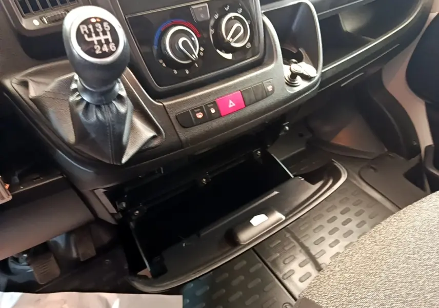 Gros plan intérieur sur la console centrale et le levier de vitesse manuel du Fiat Ducato Fourgon, avec boîte ouverte.