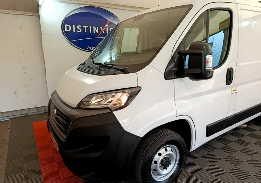 Vue 3/4 avant droit d’un fourgon FIAT Ducato blanc avec pare-chocs noirs et rétroviseur large noir.