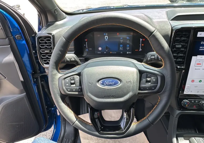 Vue intérieure centrée sur le volant cuir noir avec surpiqûres marron du Ford Ranger Bleu Lightning 2025.