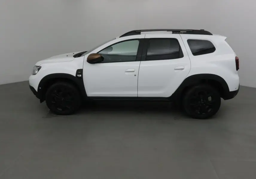 Profil côté gauche du Dacia Duster 4x4 blanc 2024 avec jantes noires et coques de rétroviseurs marron.