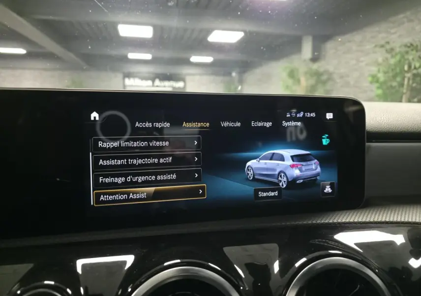 Écran multimédia affichant les aides à la conduite et une illustration grise côté droit de la Mercedes Classe A AMG Line.
