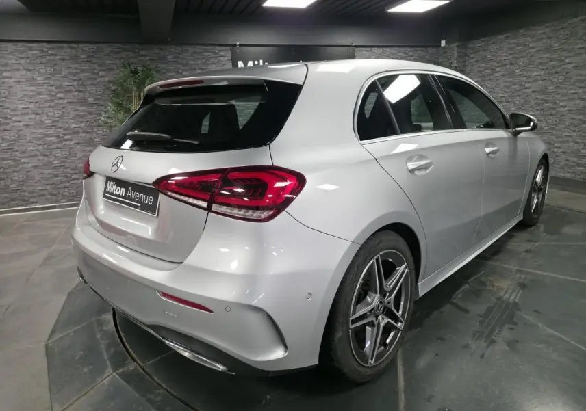 Vue 3/4 arrière droite d'une Mercedes Classe A gris métallisé avec jantes AMG et feux arrière LED dans un showroom.