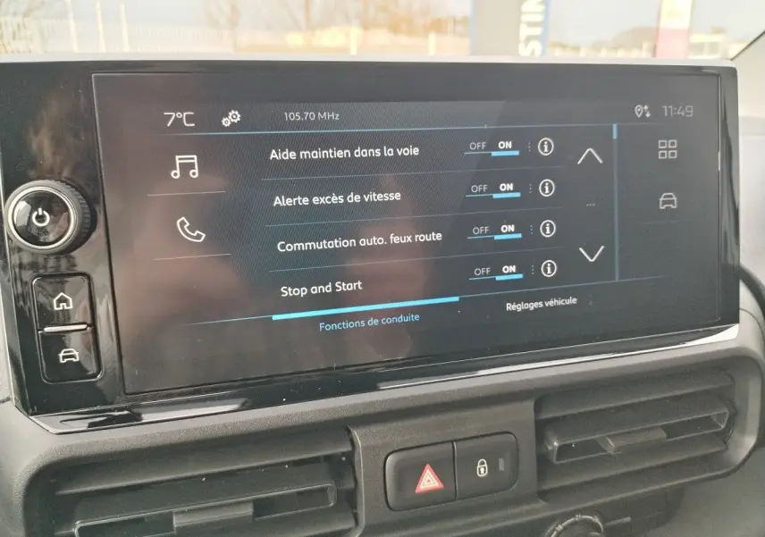 Vue intérieure centrée sur l'écran tactile du tableau de bord du Peugeot Partner Fourgon blanc Icy, affichant les aides à la conduite.