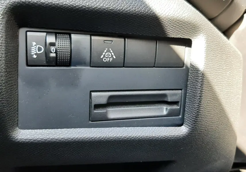 Détail du tableau de bord côté gauche du Citroën C5 Aircross noir, avec commande de réglage des phares et bouton d'assistance à la conduite.