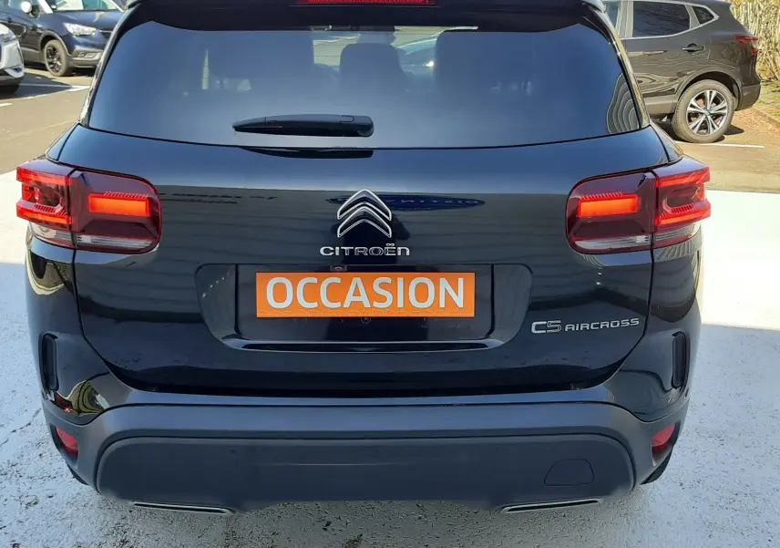 Vue arrière d'un Citroën C5 Aircross noir Perla Nera avec feux allumés et plaque "OCCASION" visible.